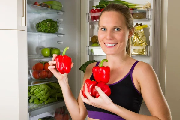 Спортивная Белая Женщина Показывает Овощи Здорового Питания Перед Холодильником — стоковое фото