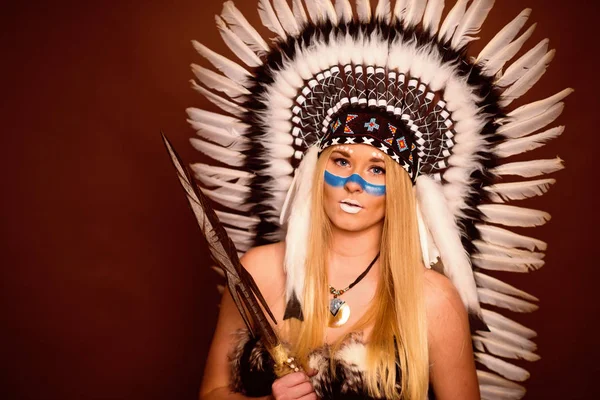 blond girl with feather headdress and spear