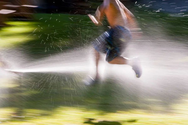 Ung Pojke Springer Genom Sprinklers Sommarsolen — Stockfoto