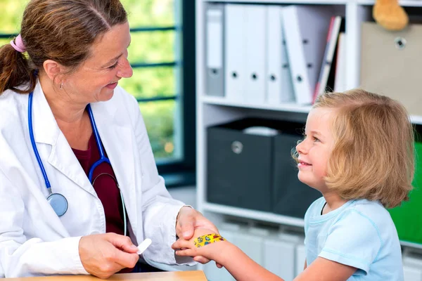 Pediatra Donna Camice Bianco Bendando Mano Una Bambina — Foto Stock