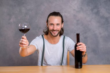 young man sitting at the table and drinking red wine clipart