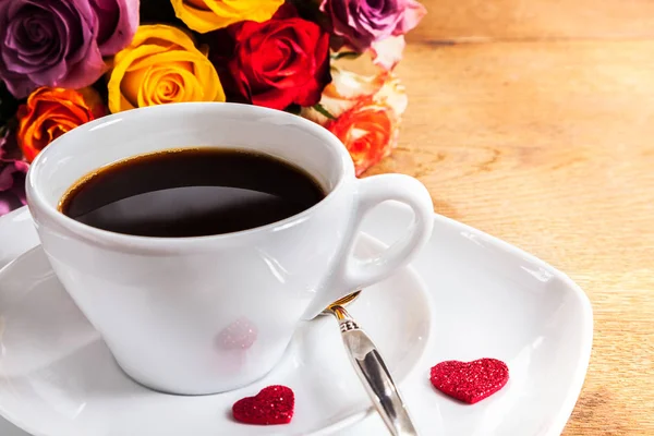 2つの赤いハートを持つバレンタインの恋人のための朝のコーヒーは 淹れたての黒コーヒーとカラフルなバラの束のソーサーに 木製のテーブルの上にスペースをコピーします — ストック写真