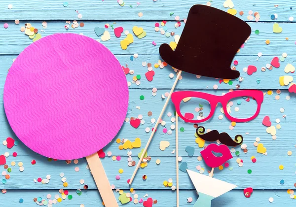 Party fun with photo booth accessories arranged as a gent in a top hat with a mustache sipping cocktails with a magenta circle with copy space alongside for your invitation or greeting