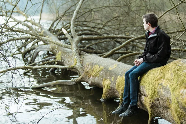 Adolescente Sentado Tronco Árbol Caído Con Vistas Tranquilo Lago Río —  Fotos de Stock