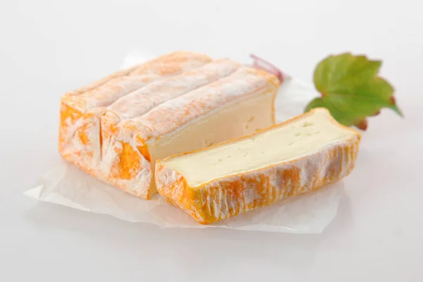 香り高い柔らかいフランスチーズのレンガは クリーミーな食感を示すためにスライスし 新鮮な葉を持つ紙ナプキンで提供 白の上に — ストック写真