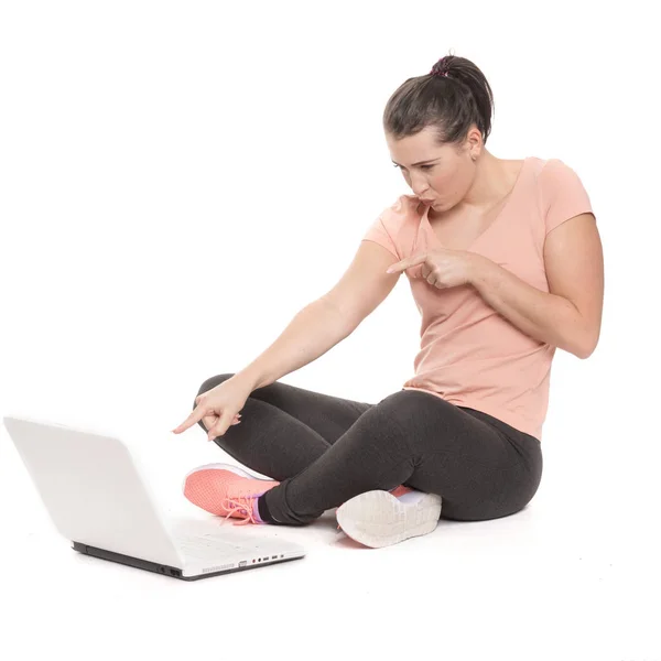 若い女性がノートパソコンに座って指で指しています — ストック写真