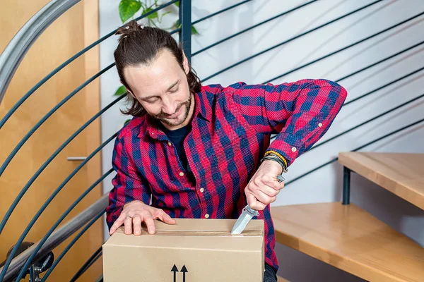 Joven Sentado Pasillo Abriendo Paquete — Foto de Stock