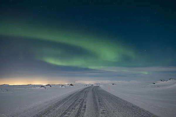 凍った山道の上の空に舞う北の光 — ストック写真