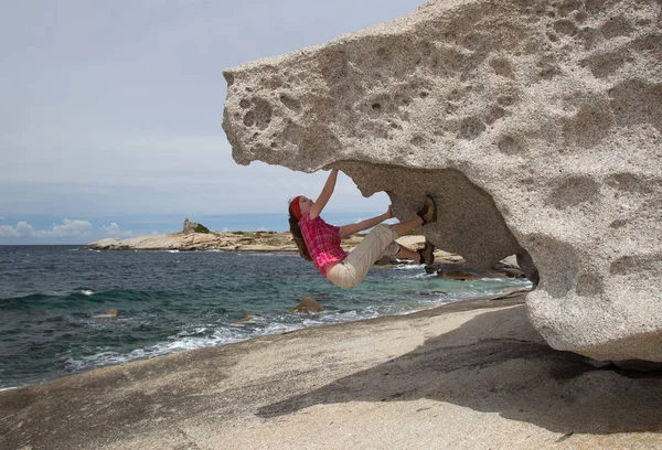 若い女性がカルビの近くの海岸の岩の上で岩の上で岩の上でボルダリング U200B U200Bcorsica — ストック写真