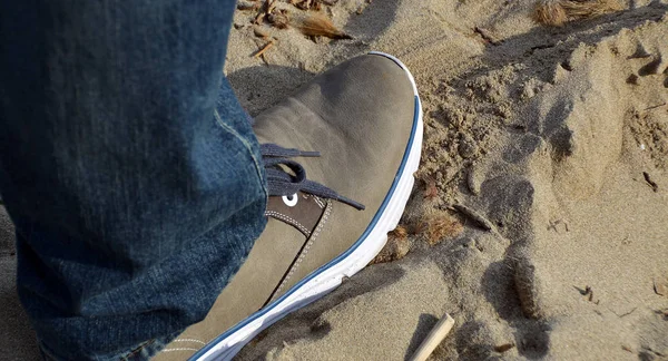 close up of a man's feet with a skateboard on the beach