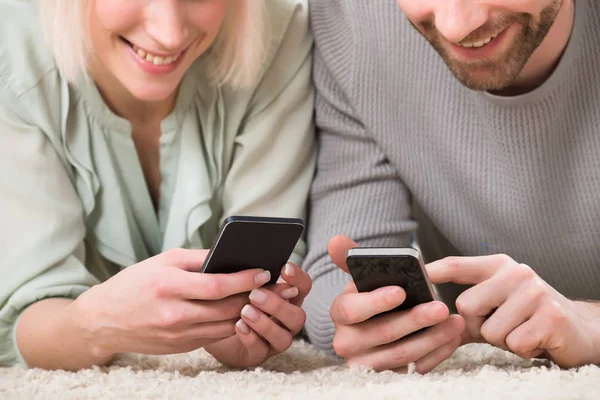 Gros Plan Couple Tenant Des Téléphones Cellulaires Tout Étant Allongé — Photo