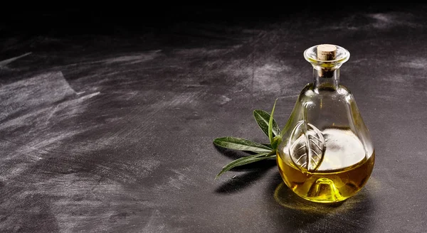 用橄榄油枝条在涂有面粉的深色计数器表面上封闭橄榄油装饰玻璃瓶的静止寿命及充分复制空间 — 图库照片