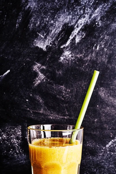 黒の黒板を背景にしたグラスを飲みながらマンゴー風味のスムージーの上半分にクロップビューを閉じ スペースをコピー — ストック写真