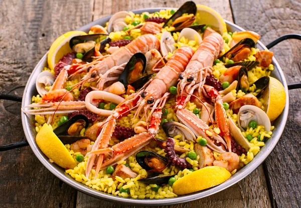 Close Up Overview of Colorful Spanish Seafood Paella Dish Served in Shallow Bowl on Rustic Wooden Table