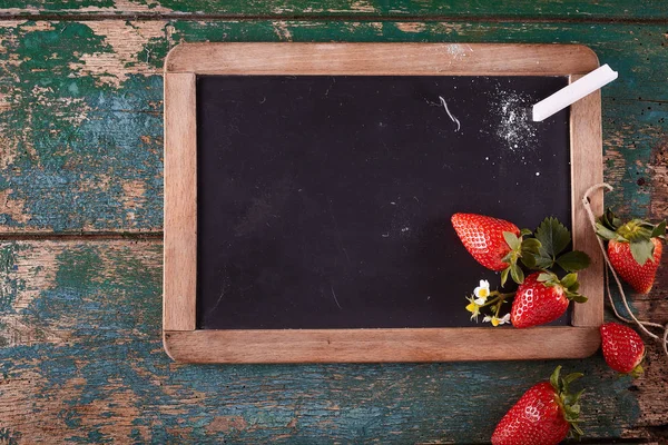 角にチョークピースと熟したイチゴの果物を使用した空白の長方形の黒い黒板 — ストック写真