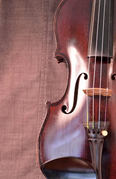 古老的小提琴与灰色的缝纫布相抗衡 小提琴是19世纪初的一种带有深色污迹的古董 — 图库照片