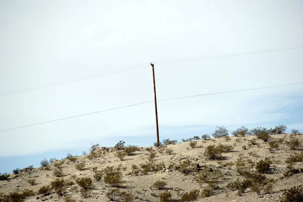 一座电杆矗立在一座荒芜的沙漠中的山丘上 — 图库照片