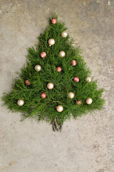 Weihnachtsbaum Aus Zedernzweigen Mit Pfirsichfarbenem Und Rosafarbenem Kugelschmuck Vor Betonhintergrund — Stockfoto