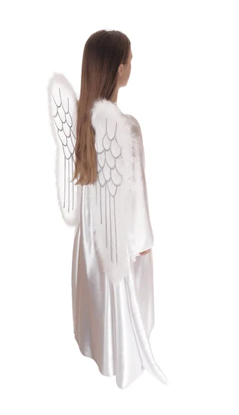 長い白いサテンのドレスに翼と長い茶色の髪を持つ天使 白い背景のために隔離されたプロフィールに立つ — ストック写真