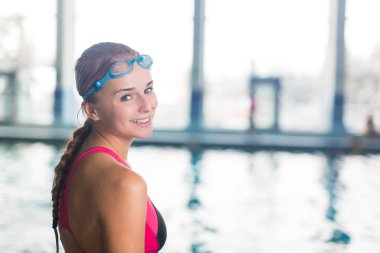 Female swimmer in an indoor swimming pool - looking at the camera, smiling wholeheartedly (shallow DOF clipart