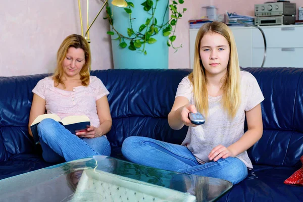 Ξανθιά Γυναίκα Διαβάζει Ένα Βιβλίο Και Κόρη Της Βλέπει Τηλεόραση — Φωτογραφία Αρχείου