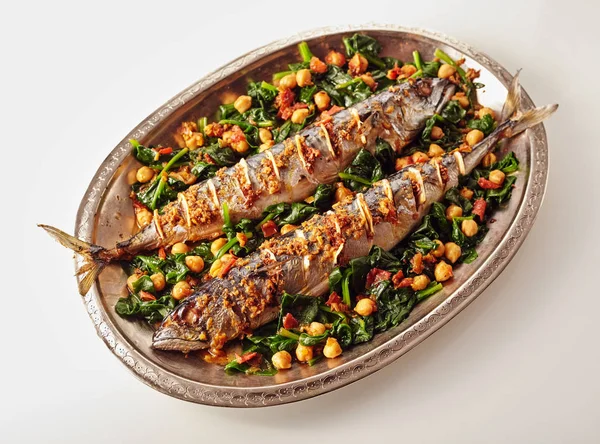 スパイスを詰め ガルバンゾエンドウ豆や野菜で飾られた2つの全体の調理サバ魚の完全な単楕円形の銀皿 — ストック写真