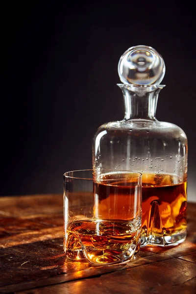 黒を背景に丸みを帯びた木製のテーブルの上にデカンタ以外のウイスキーのガラス — ストック写真