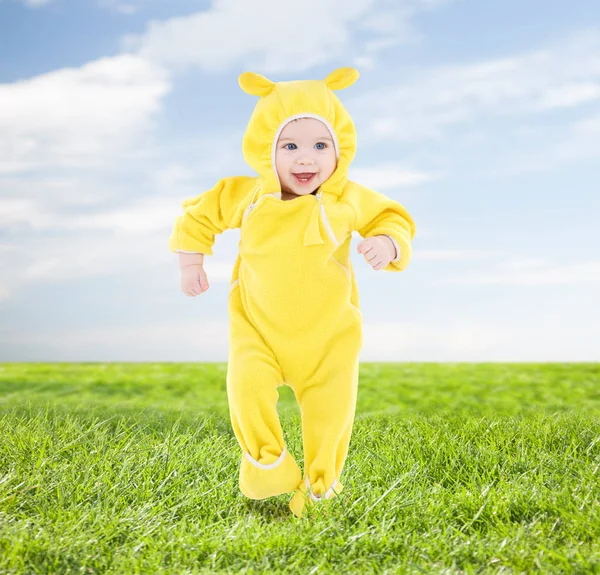 達成と幸福の概念 青空と草の背景の上に最初のステップを作る黄色のスーツで幸せな赤ちゃん — ストック写真