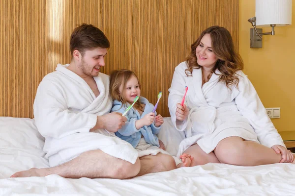 Una Familia Feliz Con Cepillos Dientes Sienta Una Cama Habitación —  Fotos de Stock