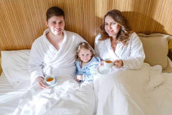 甘い娘を持つ若い両親は 午前中に寝室のベッドの上にあります 幸せな家族 — ストック写真