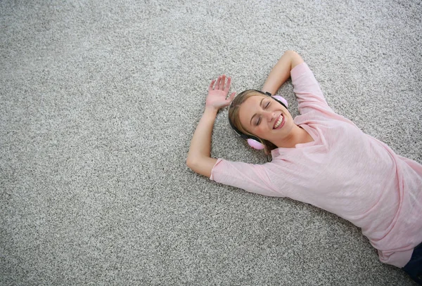 ブロンド女の子リラックスカーペットの床にヘッドフォンでオン — ストック写真