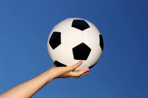 soccer ball in hand on blue background