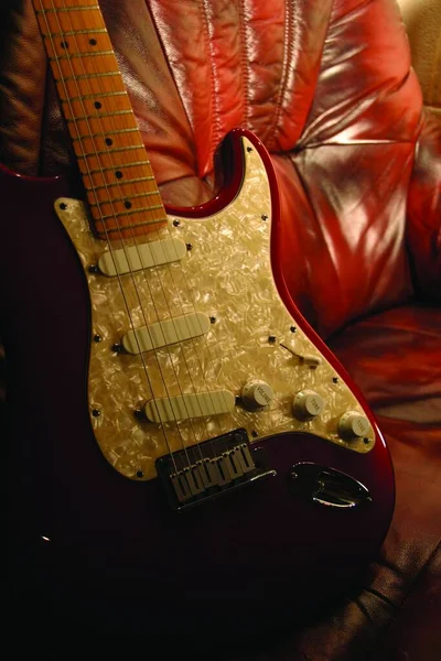 Una Guitarra Eléctrica Roja Moderna Que Apoya Una Silla Cuero —  Fotos de Stock