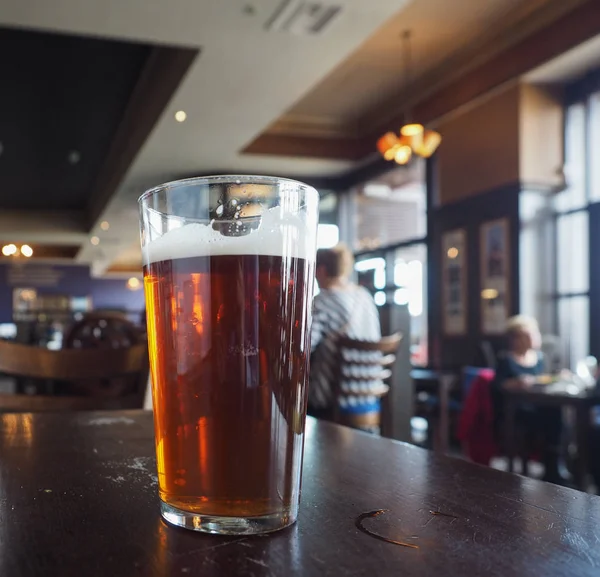 パブで英国のエールビールのパイント 背景がぼやけてガラスに選択的な焦点 — ストック写真