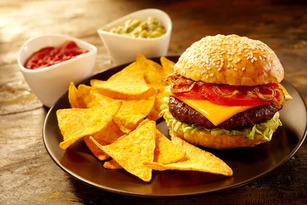 Delicious Large Cheeseburger Topped Tomatoes Onions Alongside Triangular Nacho Chips — Stock Photo, Image
