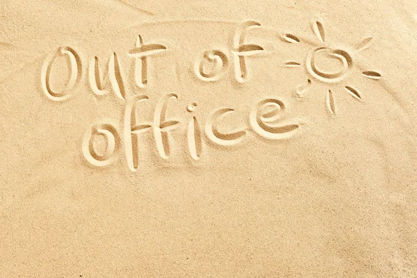 Out of office sign scribbled on beach sand with a hot shining sun and copy space conceptual of spring and summer breaks in tropical destinations