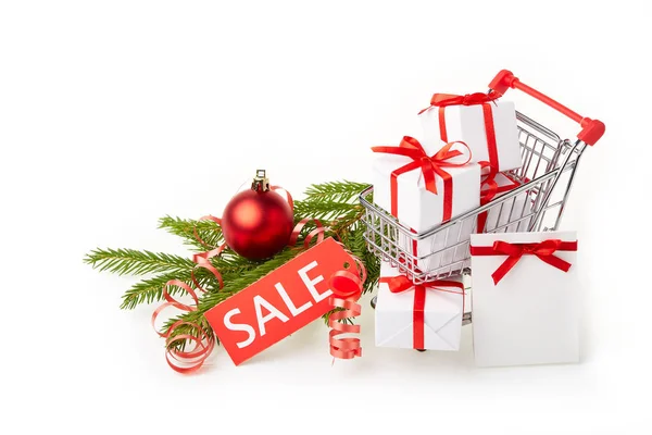 ギフトボックスと白い背景に装飾が施されたモミの木の枝を持つショッピングトロリー クリスマスと新年の販売 — ストック写真