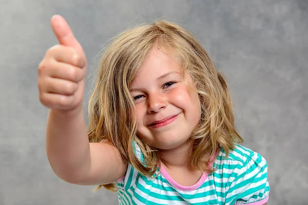 Śmieszne Dziewczyna Kciuk Górę Przed Szarym Tle — Zdjęcie stockowe