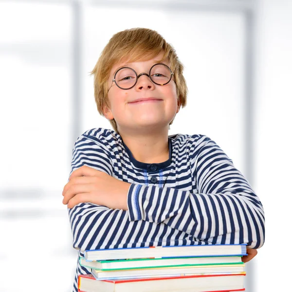 本の山に丸い眼鏡をかけた金髪の少年 — ストック写真