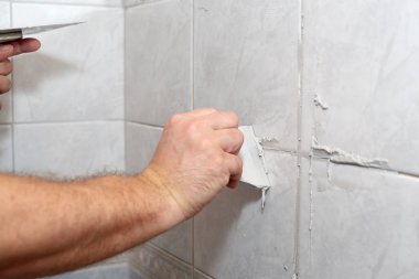 Male worker tiling a wall. clipart