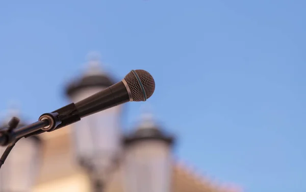 A music microphone against a blue sky in the summer at an outdoor concert