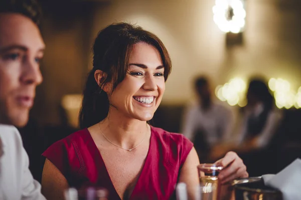 Close up of a mature woman at a restaurant. She is enjoying a glass of champagne with her friends.