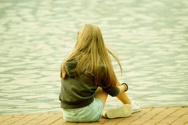 水の近くに座っている若い女の子は — ストック写真