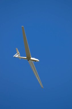 a glider against a blue sky glides through the air without its own engine drive. clipart