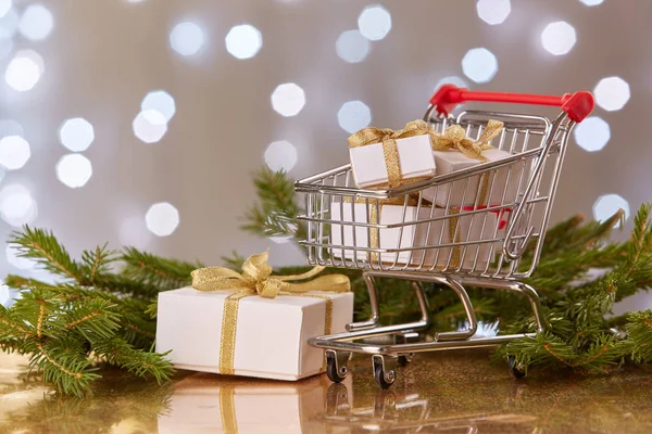 Einkaufswagen Mit Geschenkboxen Und Tannenzweigen Mit Dekoration Auf Grauem Hintergrund — Stockfoto