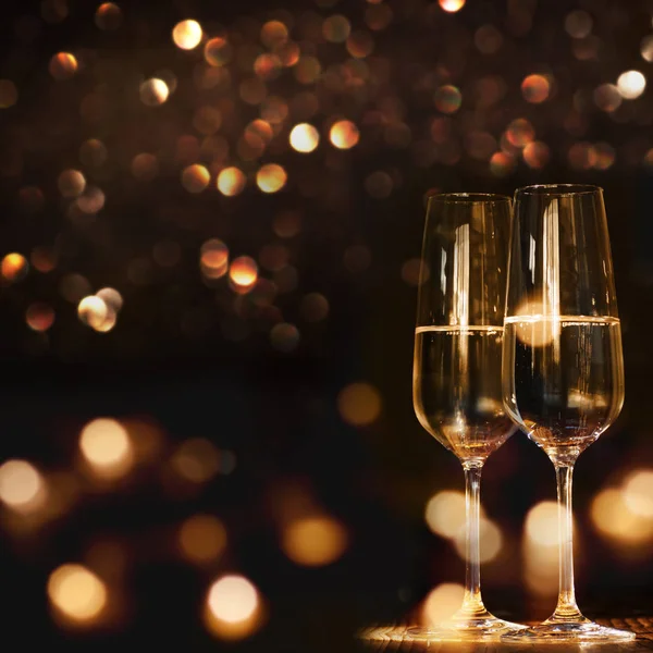 champagne glasses against a dark background with gold shimmering light