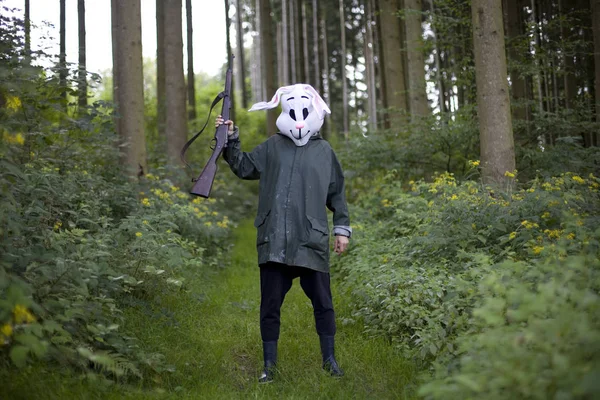 戴着兔子面具的女人拿着猎枪在森林里打猎 — 图库照片