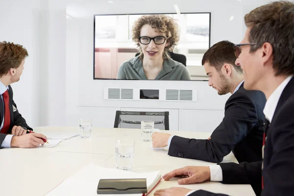 Empresários Sentados Torno Mesa Conferência Tendo Videoconferência Com Mulher — Fotografia de Stock