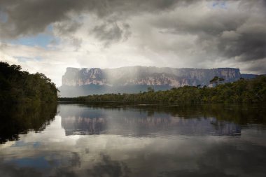 Tepuis, large flat topped mountains, stand all along the winding Canaima River, in Canaima National Park, Venezuela. Auyantepui seen here is home to Angel Falls clipart