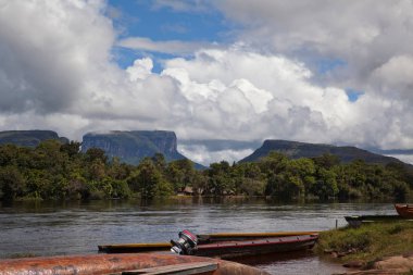 Dugout canoes moored on the Canaima River. Tepuis, large flat topped mountains, stand all along the winding river, in Canaima National Park, Venezuela clipart